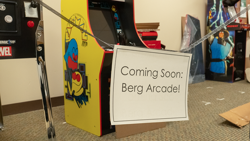 A sign that says "Coming Soon: Berg Arcade!" with several arcade cabinets actively being built in the background.