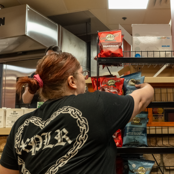 A member of the Parkhurst Staff adding potato chip bags to a display in the new Rock Creek Cafe and Bakery